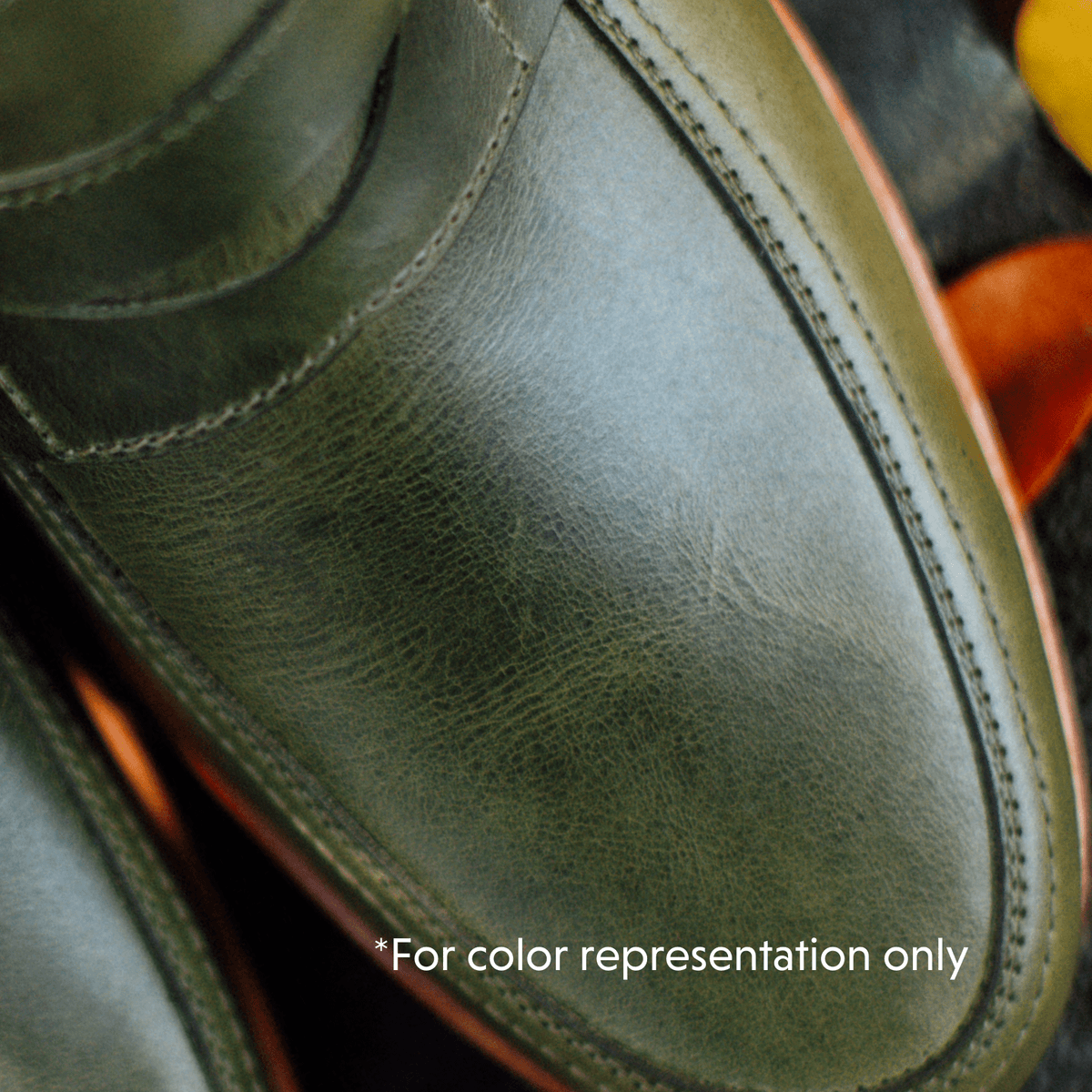 Close up of a green leather womens penny loafer with textured grain and detailed stitching