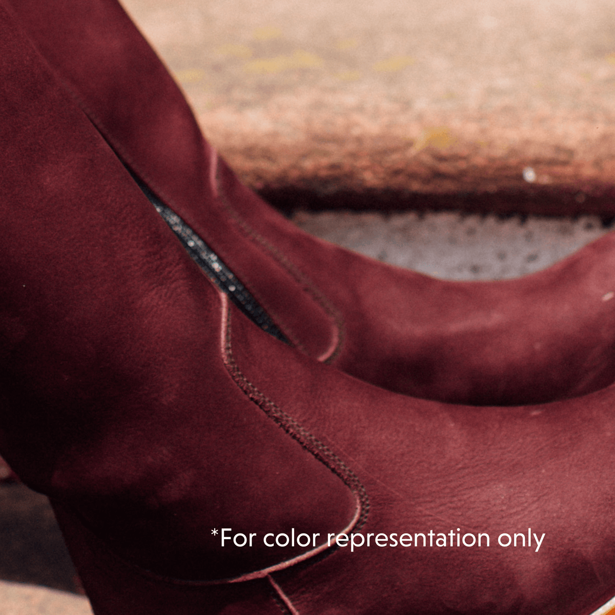 Close-up of a burgundy leather women's riding boot with stitched wraparound detailing and a tall shaft