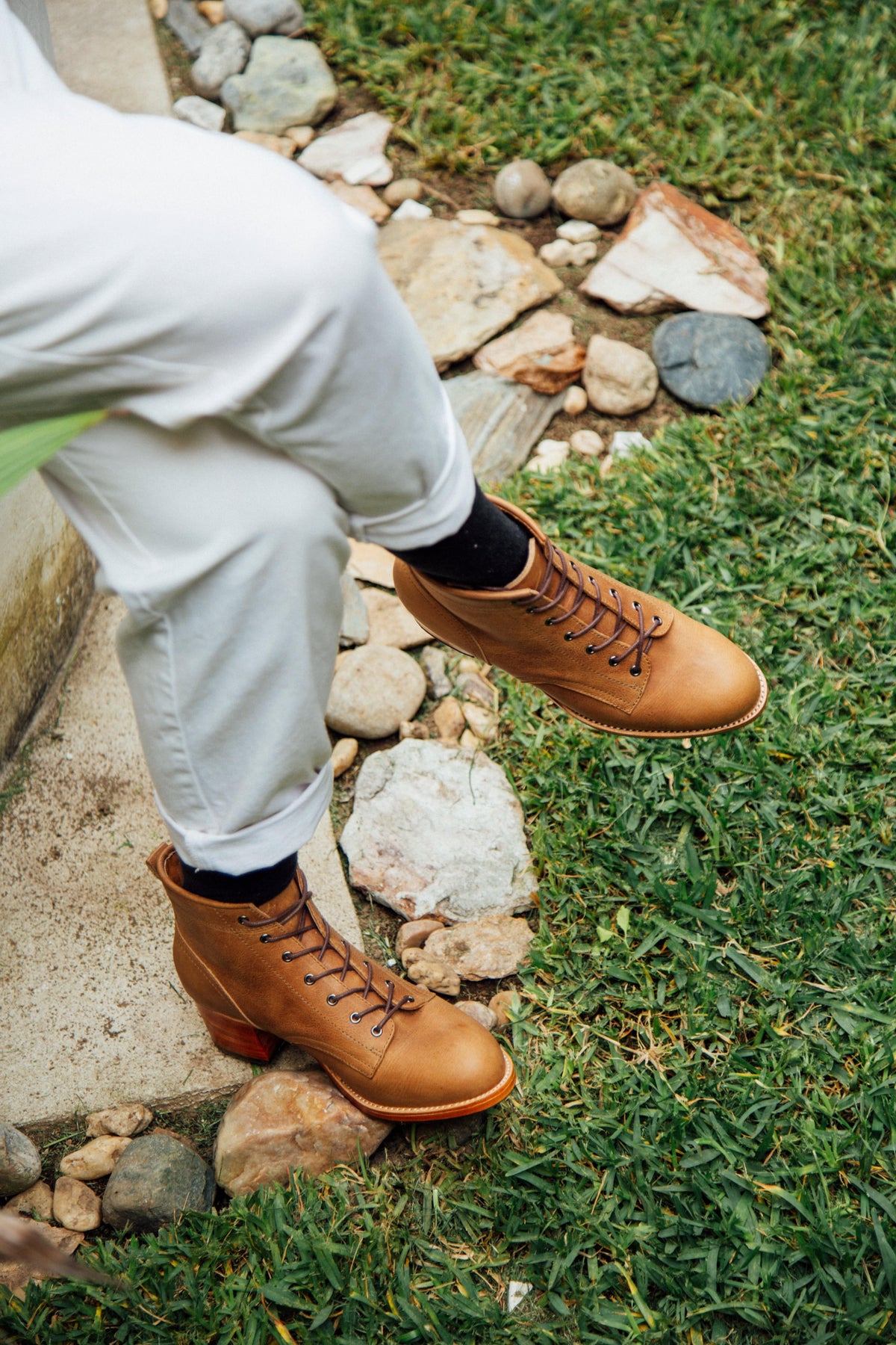 Brown leather women's lace-up combat boots with sturdy soles and 2-inch block heels worn outdoors