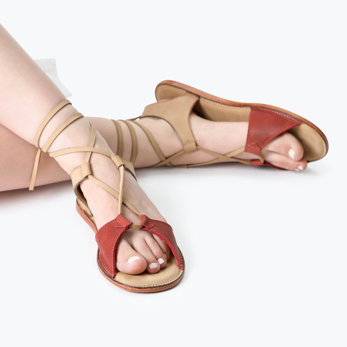 Women's tan and red gladiator sandals with wraparound laces and open toes, handcrafted by Adelante artisans