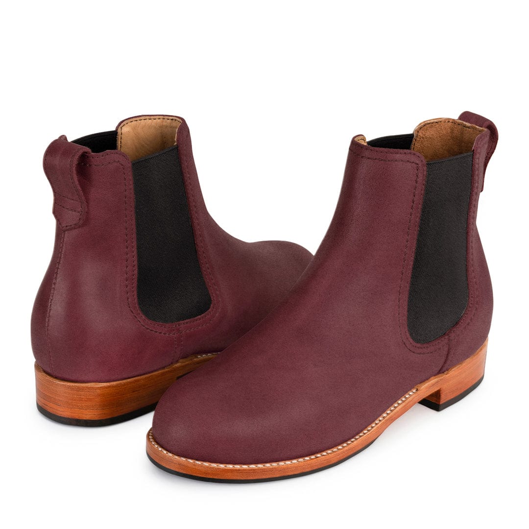Burgundy women's Chelsea boots with black elastic side panels, pull tabs, contrast stitching, and wood toned soles, available in wide widths