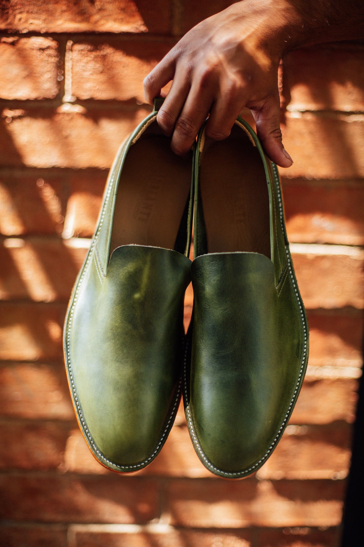 Men's 2E-wide green leather slip-ons, in a lifestyle shot, can be made in size 6.5 – The Viento