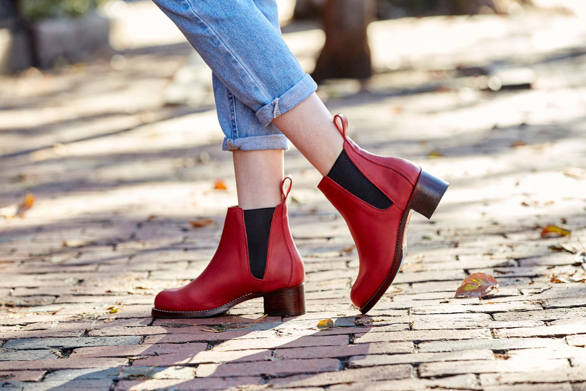 Size 12 women's red leather Chelsea boots with black elastic sides and stacked block heels, worn with cuffed jeans on a brick street